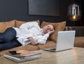 Tired mature businessman sleeping on couch in office or at home. Overtime work or overload at work concept. Royalty Free Stock Photo