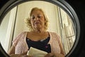 mature woman with closed eyes doing laundry seen from inside the washing machine Royalty Free Stock Photo