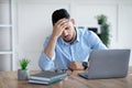 Tired millennial Arab businessman suffering from headache at desk in modern office