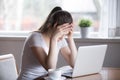 Tired millennial woman sitting at laptop working at home