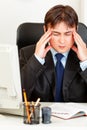 Tired modern businessman sitting at office desk