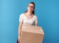 Tired modern woman in white shirt with cardboard box on blue