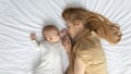 Tired mom and cute peaceful baby sleeping on mattress