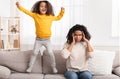 Tired Mother Covering Ears, Daughter Jumping On Couch At Home Royalty Free Stock Photo