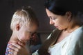 Tired mother hugging and calming little cute sad upset crying caucasian blond toddler boy at home indoor. Mom holding sleepy sick Royalty Free Stock Photo