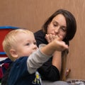 Tired mother looks at cheerful blond son 3 years old little boy telling a story