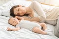 Tired mother sleeping with her newborn son, exhausted after babycare