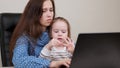 Tired mother works with a laptop and plays with her little daughter. Mom working and raising children. Business woman in Royalty Free Stock Photo