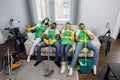 Tired multiracial cleaners relaxing together on couch