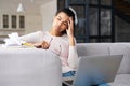 Tired multiracial young woman sitting on the sofa with laptop and looking away Royalty Free Stock Photo