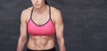 Tired muscular sporty woman in a pink sports bra doing exercise at a studio.