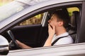 Tired novice driver  yawning while driving his car. Exhausted young guy stop driving his car for resting Royalty Free Stock Photo