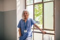 Tired nurse taking break, standing by old widnow. Royalty Free Stock Photo