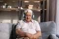 Tired old man listening to music from big wireless headphones Royalty Free Stock Photo