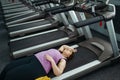 Tired overweight woman lying on treadmill in gym Royalty Free Stock Photo