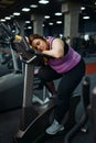 Tired overweight woman sleeps on exercise bike