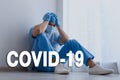 Tired overwhelmed doctor sitting on floor in hospital. Medical system collapse during coronavirus pandemic Royalty Free Stock Photo