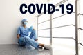 Tired overwhelmed nurse sitting on floor in hospital. Medical system collapse during coronavirus pandemic Royalty Free Stock Photo