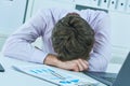 Young tired overworked businessman sleeping over a laptop in a desk at job in his office. Deadline concept. Royalty Free Stock Photo