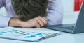 Young tired overworked businessman sleeping over a laptop in a desk at job in his office. Deadline concept. Royalty Free Stock Photo