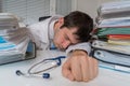 Tired and overworked doctor is sleeping on desk in office