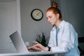 Tired overworked redhead young woman working typing on laptop computer sitting at table Royalty Free Stock Photo