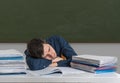 Tired overworked teacher is sleeping on desk in classroom