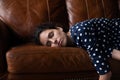 Tired peaceful Latin woman with closed eyes lying on sofa