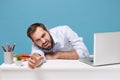 Tired perplexed young man in shirt sit work at desk with pc laptop isolated on blue background. Achievement business Royalty Free Stock Photo