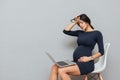 Tired pregnant business woman sitting over grey background Royalty Free Stock Photo