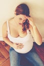 Tired pregnant woman with headache sitting on the floor Royalty Free Stock Photo