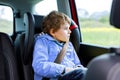 Tired preschool kid boy sitting in car during traffic jam. Sad little school child in safety car seat with belt enjoying Royalty Free Stock Photo