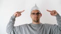 White serious attractive man in a foil hat points his fingers at the tinfoil hat. 5G tower radiation protection. Irrational fear