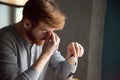 Tired millennial man massaging nose feeling fatigue from work