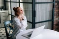 Tired redhead young business woman having neck pain during working at laptop compute