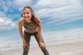 Tired female runner in headphones sweating after cardio exercise and rest after finish on beach Royalty Free Stock Photo