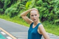 Tired runner sweating after running hard in countryside road. Exhausted sweaty woman after marathon training on hot