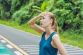 Tired runner sweating after running hard in countryside road. Exhausted sweaty woman after marathon training on hot