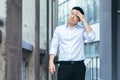 Tired and sad Asian has a severe headache, a businessman outside the office, holding hands behind his head Royalty Free Stock Photo