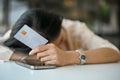 Tired and sad Asian woman laid her head down on the table, holding a credit card Royalty Free Stock Photo