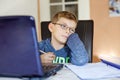 Tired sad kid boy with glasses making school homework at home with notebook. Depressed child writing essay with helping Royalty Free Stock Photo