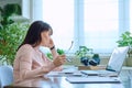 Tired sad mature woman at workplace at table with computer laptop