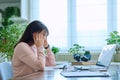 Tired sad mature woman at workplace at table with computer laptop