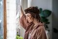 Tired sad serious pensive teen girl in eyeglasses standing near window looking down at home. Royalty Free Stock Photo