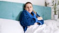 Portrait of tired sad woman in bathrobe lying in bed at home Royalty Free Stock Photo