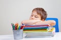 Tired school boy sleeps sitting at the table with big pile of books, textbooks and notebooks Royalty Free Stock Photo