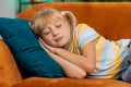 Tired school girl child kid lying down in bed taking a rest at home, napping, falling asleep on sofa Royalty Free Stock Photo