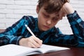 Tired schoolboy falling asleep while studying at copybook. Study