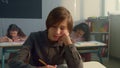 Tired schoolboy sitting in classroom. Cheerful boy boring during lesson Royalty Free Stock Photo