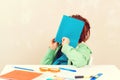 Tired schoolboy sitting at table. Boy covered face with notebook Royalty Free Stock Photo